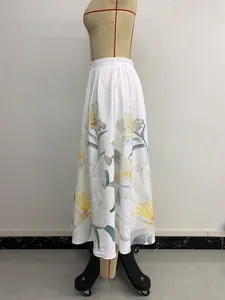 Detail of white A-line midi skirt featuring yellow floral prints and elastic waistband