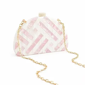 Detail of semicircular acrylic clutch with pink marble texture and gold chain strap