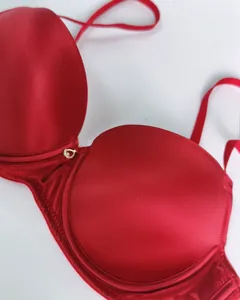 Detail view of red satin bra with underwire and gold heart pendant decoration