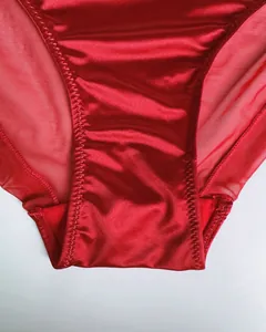 Macro detail of red satin lingerie set featuring sheer mesh panels and fine zigzag stitching