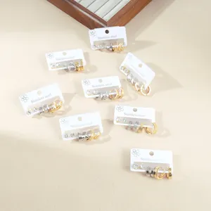 Minimalist stainless steel earring set featuring stud and hoop designs on wooden display