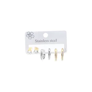 Three pairs of stainless steel earrings including gold zircon studs and small hoop earrings