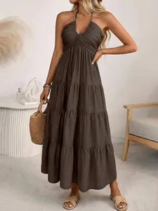 Close-up of brown halter tiered maxi dress with ruched V-neck and natural fabric texture