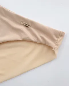 Dettaglio reggiseno beige senza cuciture con rete traspirante e placca logo dorata