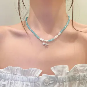 Close-up of beach-style blue beaded necklace with starfish and shell charms on model.