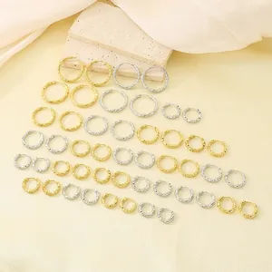 Una collezione varia di orecchini a cerchio in acciaio inossidabile testurizzato oro.