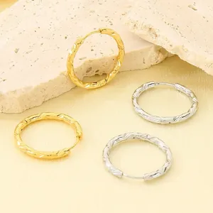 Dettaglio degli orecchini a cerchio in acciaio inossidabile con inciso motivo a rombi