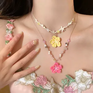 Detailed view of layered dopamine style necklaces with pink and yellow flower pendants