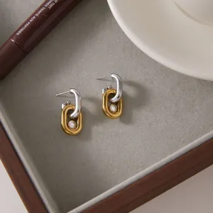 Boucles d'oreilles géométriques bicolores avec cristal dans un plateau de bijoux.