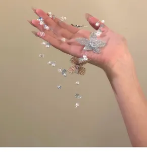 Détail d'un collier de perles et cristaux à fleurs multicouches tenu à la mano