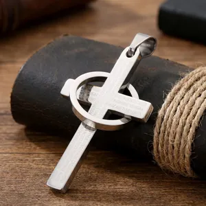 Primer plano de un colgante de cruz de acero inoxidable con grabados religiosos para hombres
