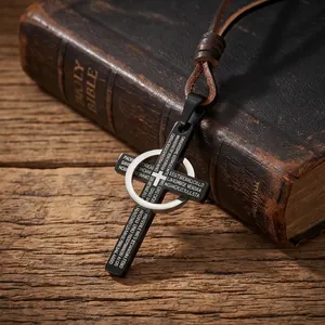 Primer plano de colgante de cruz de acero negro con cordón de cuero sobre una Biblia vieja
