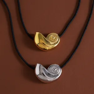 Close-up view of shell-shaped pendants in gold and silver on black cord necklaces