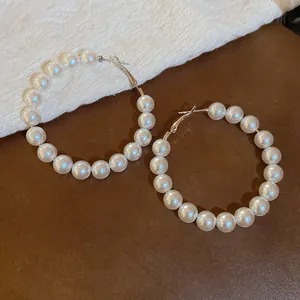 Elegante grote creolen met witte ronde parels en een glanzend goudkleurig metalen frame