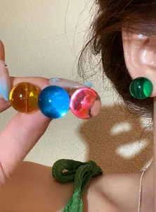 Close-up view of vibrant colorful dopamine style translucent resin round ball stud earrings