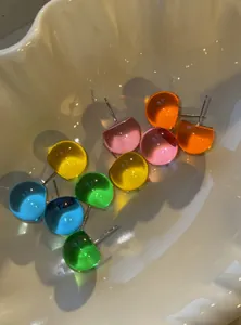 Close-up of vibrant colorful round resin stud earrings displayed in a shell dish