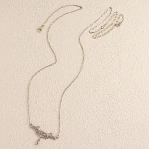 Close-up detail of a silver thorn heart body chain featuring vintage carvings and orange gems.