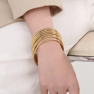 Detailed view of stacked 3mm 18k gold-plated stainless steel bangles worn on the wrist