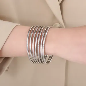 Close-up of stackable silver stainless steel bangles worn on a wrist for a chic look.