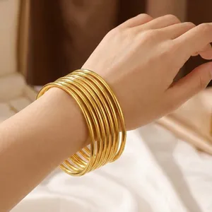 Κοντινή λήψη από 18k χρυσά βραχιόλια από ανοξείδωτο ατσάλι 3mm σε στοίβα για γυναίκες.
