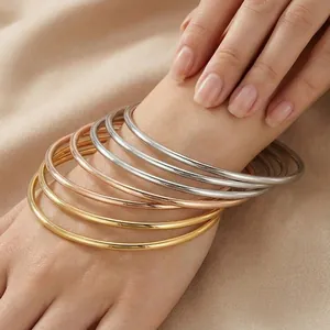 Close-up of 3mm stackable stainless steel bangles in gold, silver, and rose gold