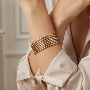 Detail view of 18k gold plated 3mm stackable stainless steel bangles worn on a wrist