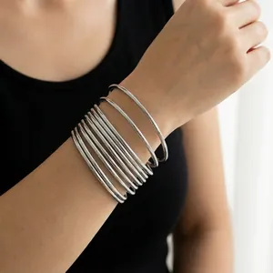Close-up view of multiple stacked 3mm silver stainless steel plain round wire bangles.