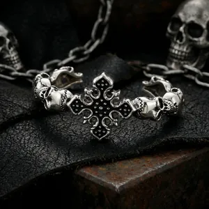 Detail of gothic stainless steel bangle featuring a cross and skulls on dark leather