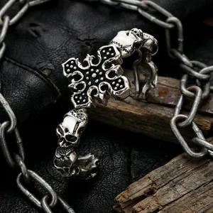 Gothic skull and cross stainless steel cuff bracelet on a dark rustic textured background