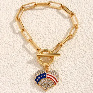 Detail of gold chain bracelet with OT buckle and heart pendant with rhinestones and enamel