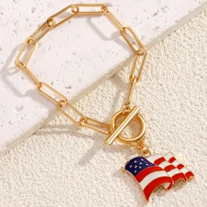 Detail of gold chain bracelet with US flag pendant and OT clasp on a textured stone