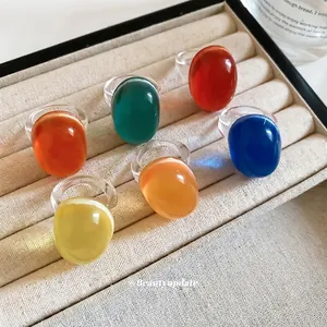 Vibrant colorful dopamine resin rings with large oval cabochons on a beige jewelry tray