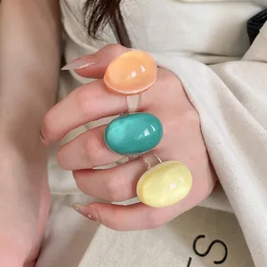 Vibrant dopamine style colorful resin oval rings displayed on a fashion model's fingers