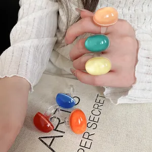 Vibrant oval resin rings shown on hand and fabric with dopamine style color palette.