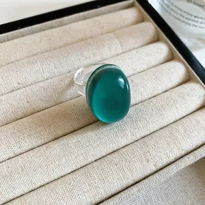 Macro detail of a translucent emerald green oval resin ring in a beige jewelry box