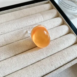 Close-up of a minimalist oval resin ring in vibrant orange on a jewelry tray
