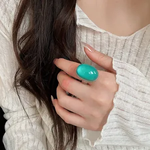 Detailed macro view of a glossy green oval resin ring worn on an index finger