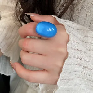 Close-up macro detail showing a bright blue oval resin ring worn on an index finger