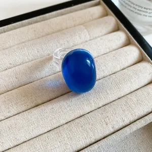 Close-up of a vibrant blue resin oval ring placed on a cream fabric jewelry tray