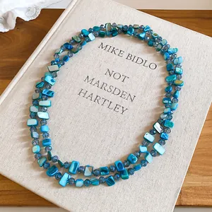 Détail d'un collier à deux rangs composé de perles de coquillage bleues irrégulières.