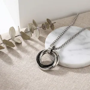 Close-up of stainless steel triple interlocking ring pendant necklace in silver and black tone.