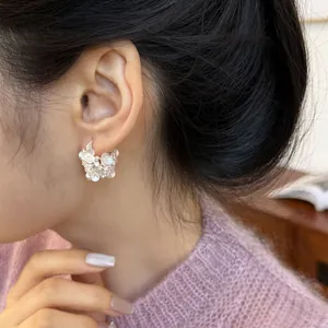 Detailed view of elegant silver flower hoop earring with pearls worn on model's ear
