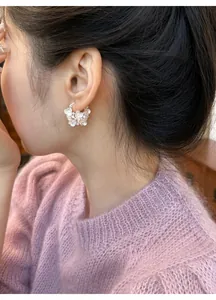 Elegant floral basket hoop earrings with pearl and crystal details on Asian model.