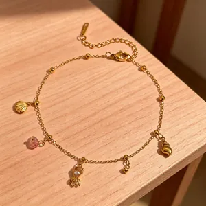 Detailed close-up of a gold stainless steel anklet with lobster and shell charms