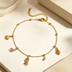 Close-up of a golden stainless steel anklet featuring sea shell and snail charms with stones