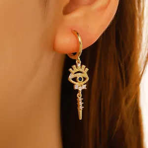 Detailed view of gold evil eye hoop earrings with blue stones and spike charms