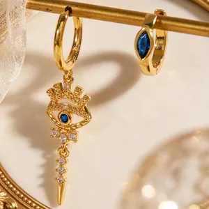 Macro detail of gold evil eye earring set with blue stones and crystals on lace background