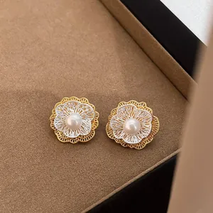 Elegant two-tone floral stud earrings with a central pearl in a luxury box setting.
