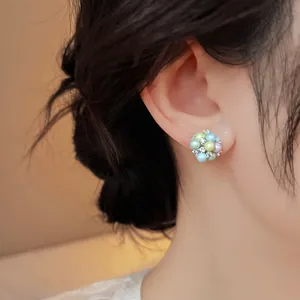 Close-up of a colorful dopamine style pastel pearl and rhinestone stud earring on ear