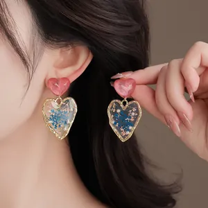 Elegant heart-shaped resin earrings with dried flowers shown on model for vacation